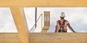 Construction worker framed by large wooden beams.