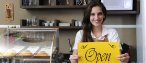Image of business owner holding open sign in bakery