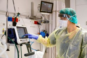 Image of medical worker operating machine wearing safety mask and other protective gear.