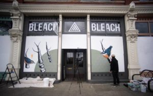 Image of artist painting windows at the retail store Bleach
