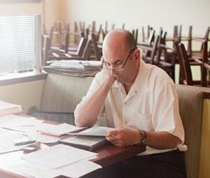 Image of man at desk looking over paperwork